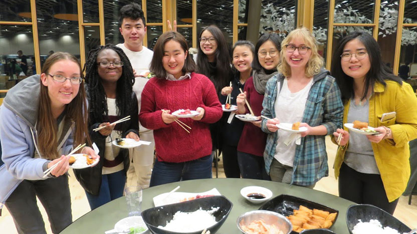 Nine students gather around a table to eat sushi