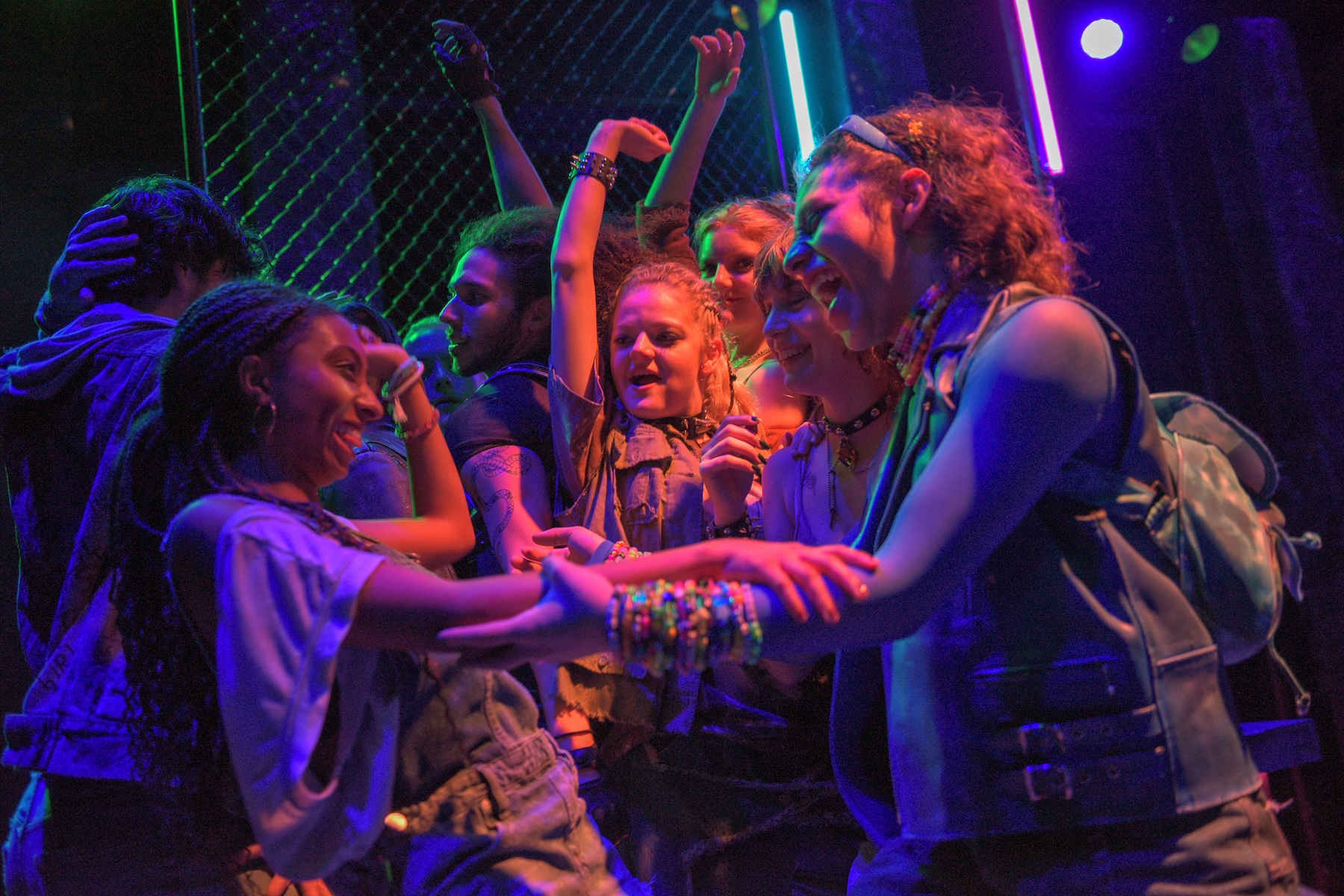 Party scene with everyone smiling and dancing, lots of colorful lighting