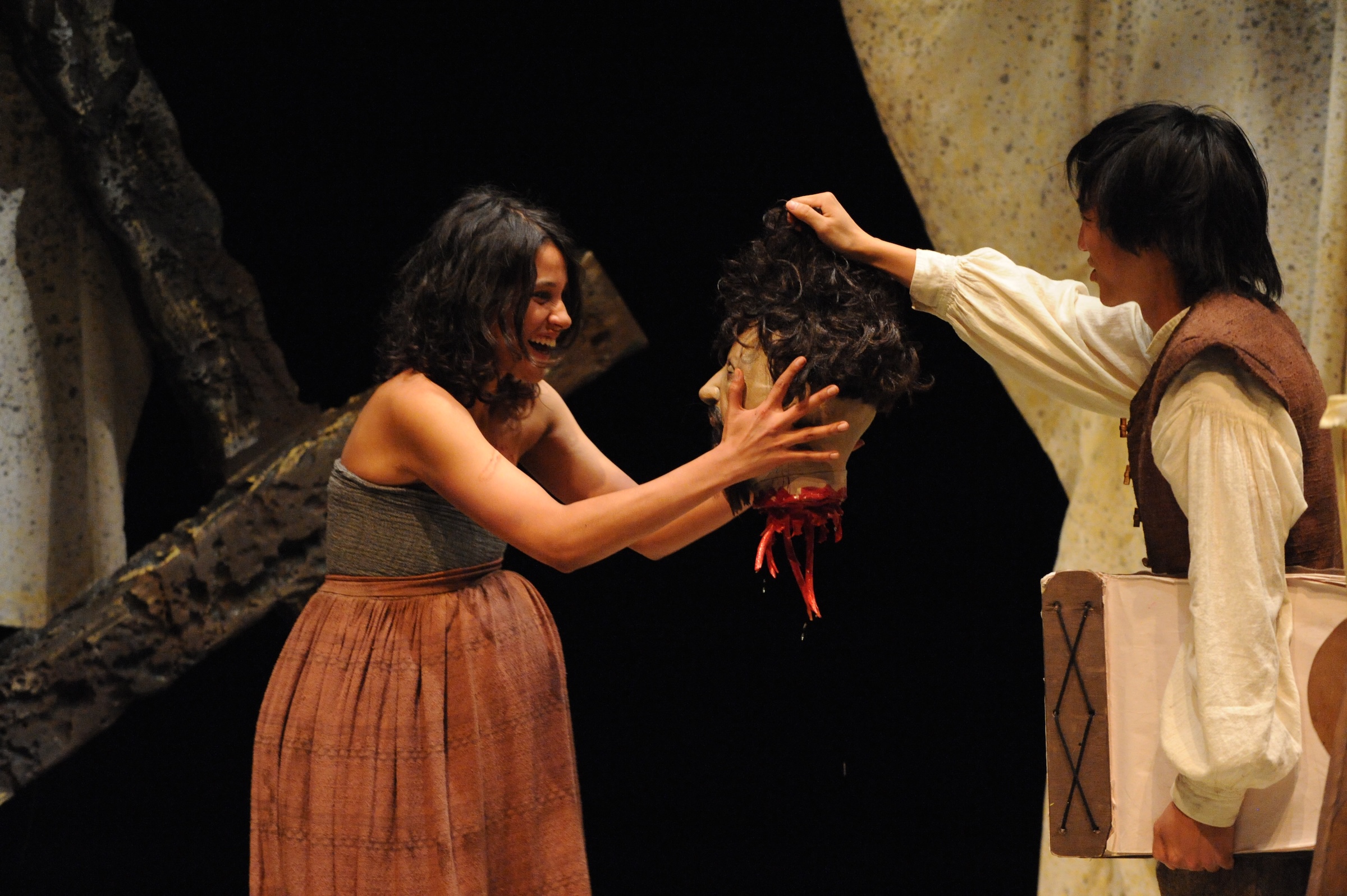 man and woman holding a decapitated head and grinning