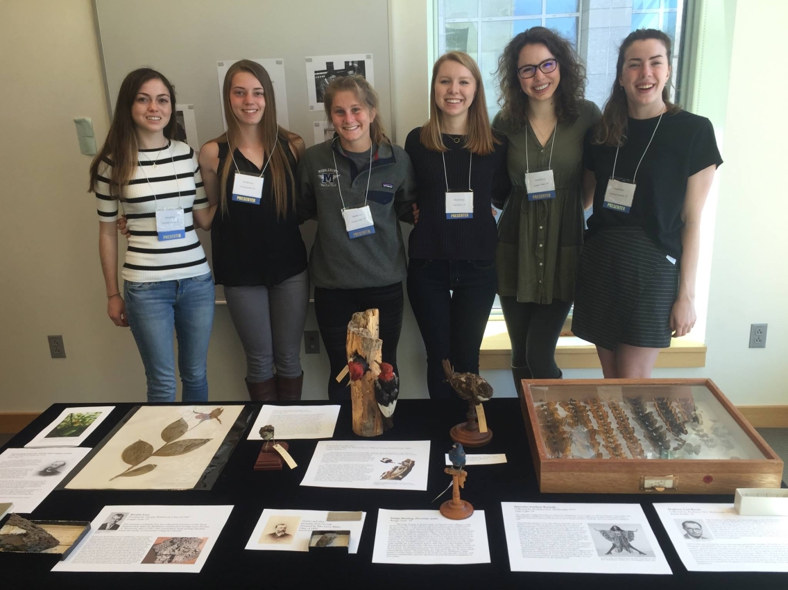 Six students stand behind the exhibit they created.