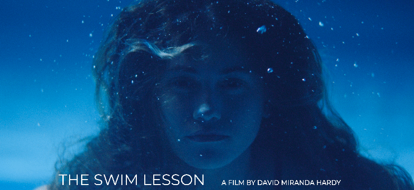 A young woman under water looking at the camera.