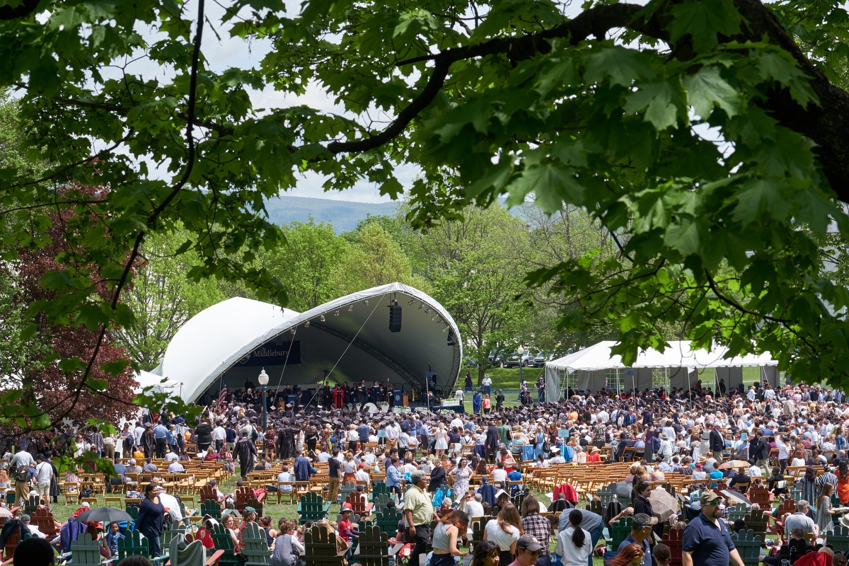 large outdoor audience with commencement tent in the background