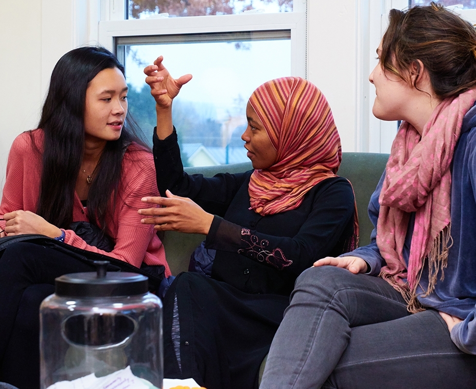 Three students talking with one another in a classroom.