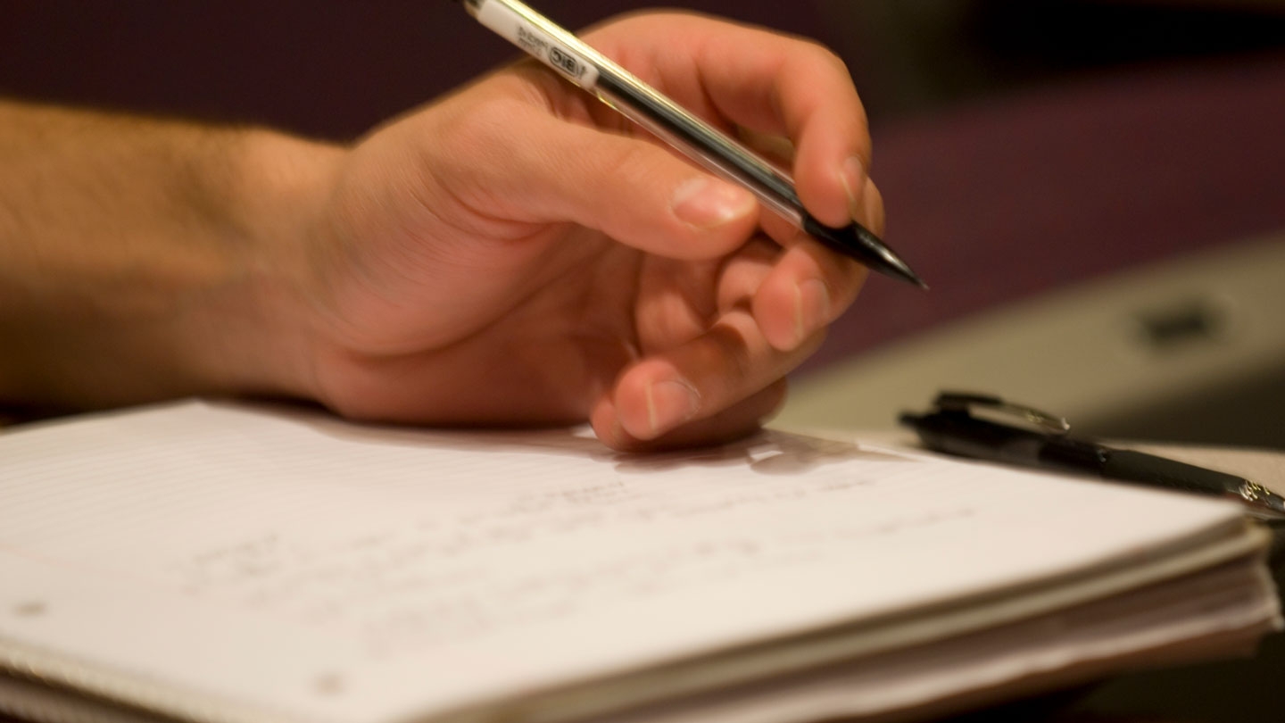 Closeup of a student writing in his notebook.