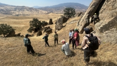 A group in a field alongside mountains.