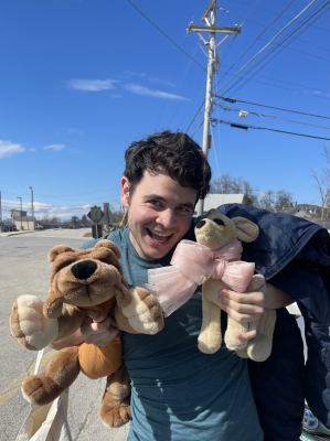 Headshot of Jonathan Mount holding stuffed animals and smiling at the camera