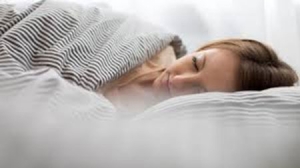 A woman sleeping under covers in a bed.