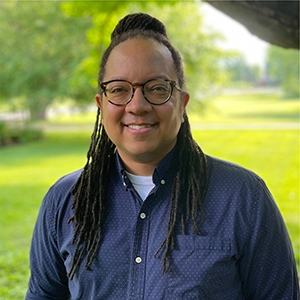 person in blue button down shirt, long dark hair, glasses