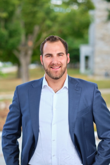 A photograph of Simon Leiderman standing outside and smiling at the camera