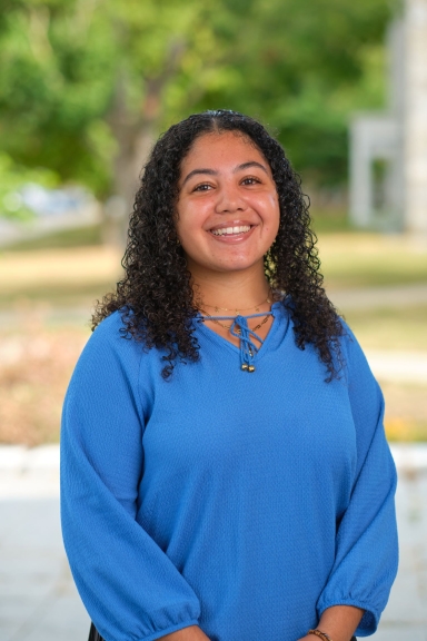 A photograph of Makayla Reed standing outside and smiling at the camera.