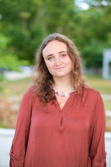 A photograph of Zoe Rosen standing outside and smiling at the camera