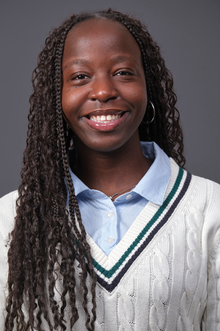 A photograph of Doreen Ngemera wearing a cream sweater and smiling at the camera
