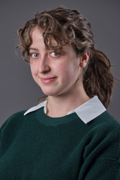 A photograph of Karolina Sciesiek wearing a green sweater and smiling at the camera