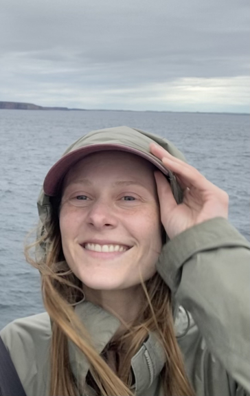 Woman in green jacket with ocean in background