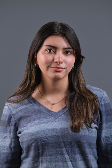 A photograph of Kimberly Barros, wearing a blue V-neck shirt and smiling at the camera.