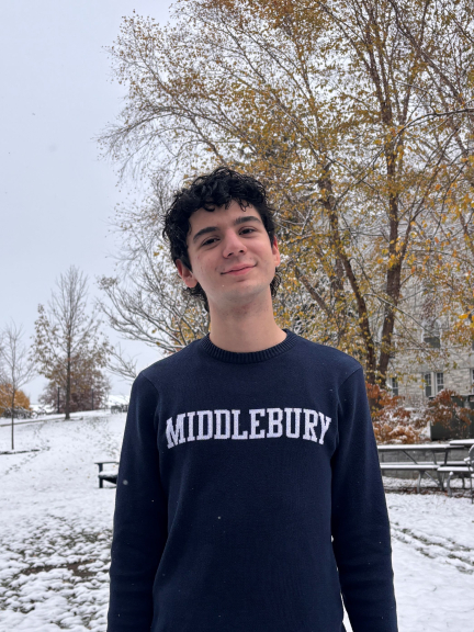 A photograph of Olt Kastrati, wearing a Middlebury sweatshirt and smiling at the camera