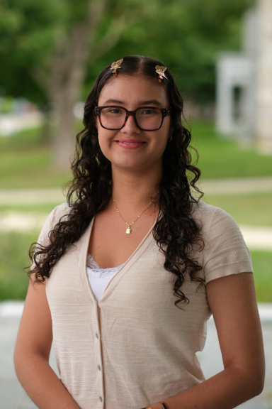 A photograph of Laura Gomez, wearing a beige top and smiling at the camera.