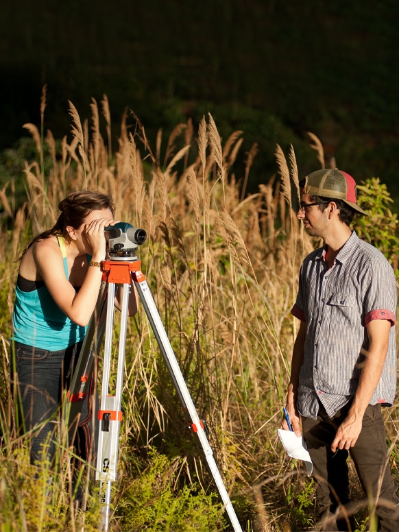 A student works in the community with a land surveyor.