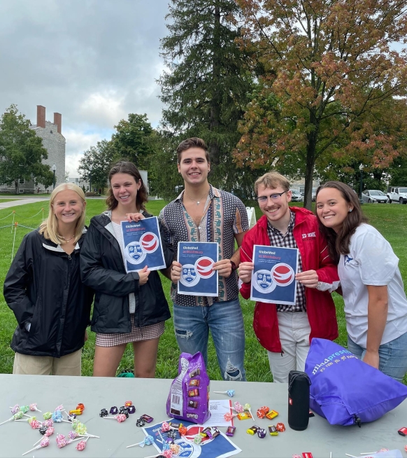 Group of GlobeMed students holding up signs at Middlebury's Club Fair