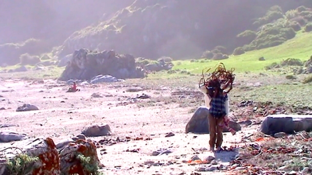 a person walking on a beach with black tape swirling around their head