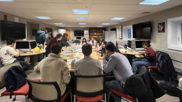 Students and faculty around a table eating lunch.