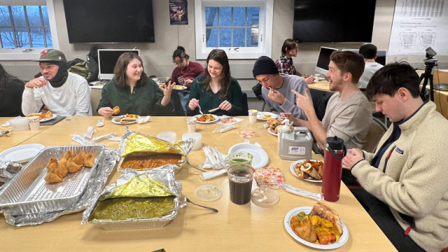 Students and faculty enjoy dinner around a table.