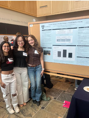 Three students stand by their poster.