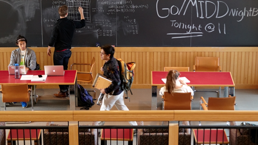 A student writes on a giant chalkboard in BiHall.