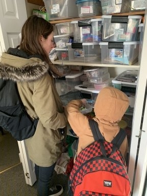 A mentor helps her young friends choose markers form the supply closet.