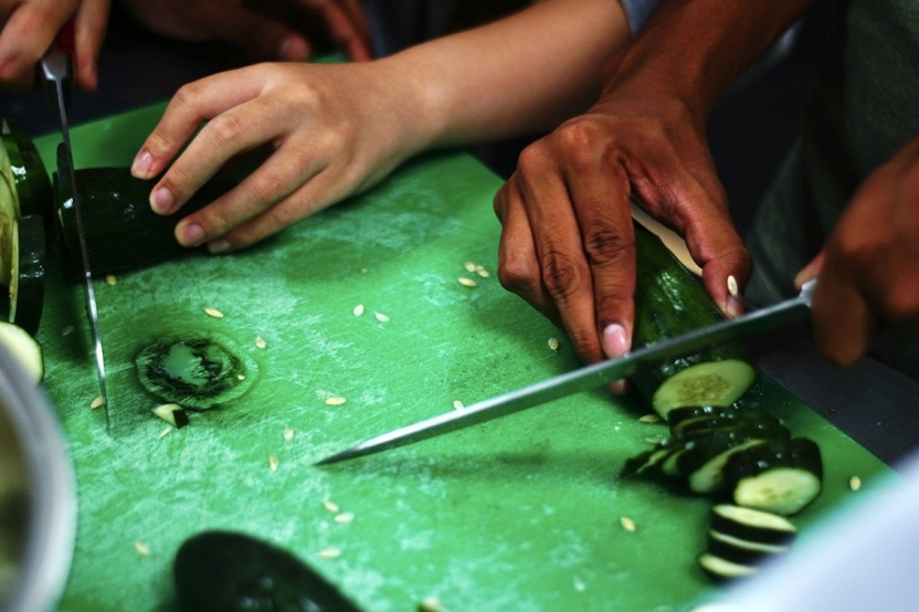 Students chopping cucumbers for dinner.