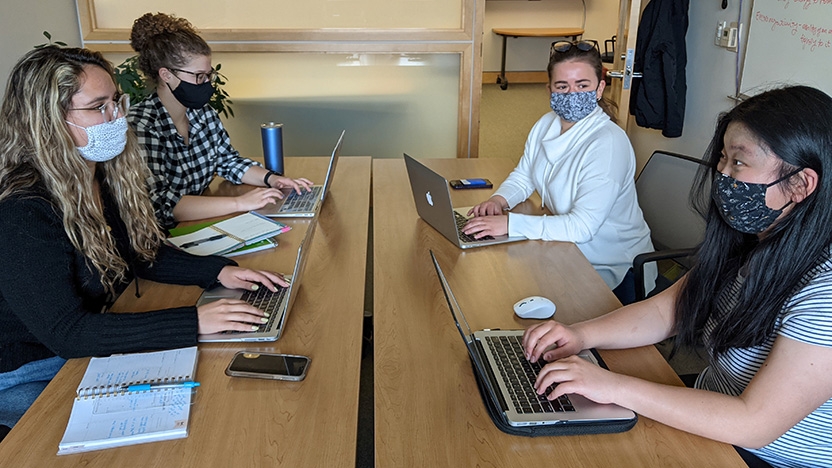 Five Midd Volunteers work on a project, sitting around a table.