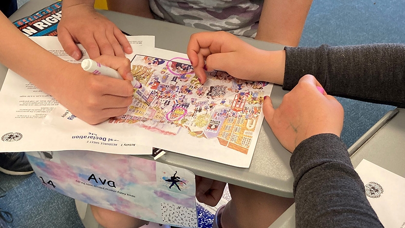 Photo of hands working on a language in motion project with an elementary school student