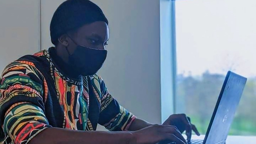 Student Sam Kamau works at his laptop.