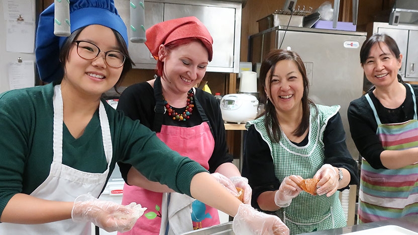 Four students make sushi in a kitchen