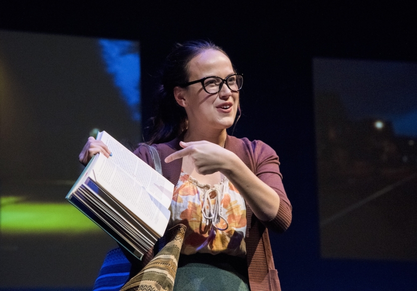 Actress wearing glasses pointing at open book