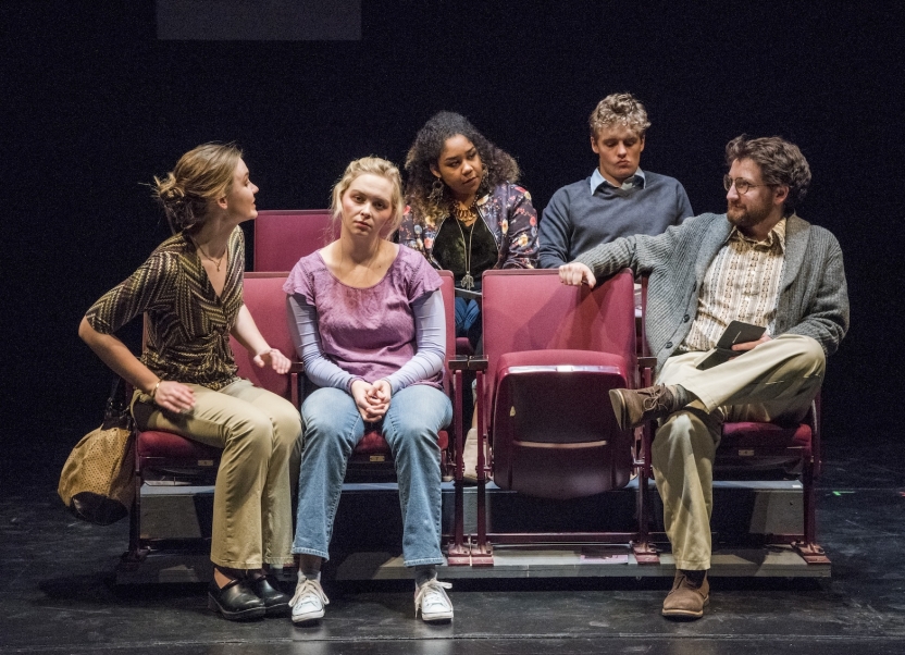 Five actors seated on two rows of chairs talking