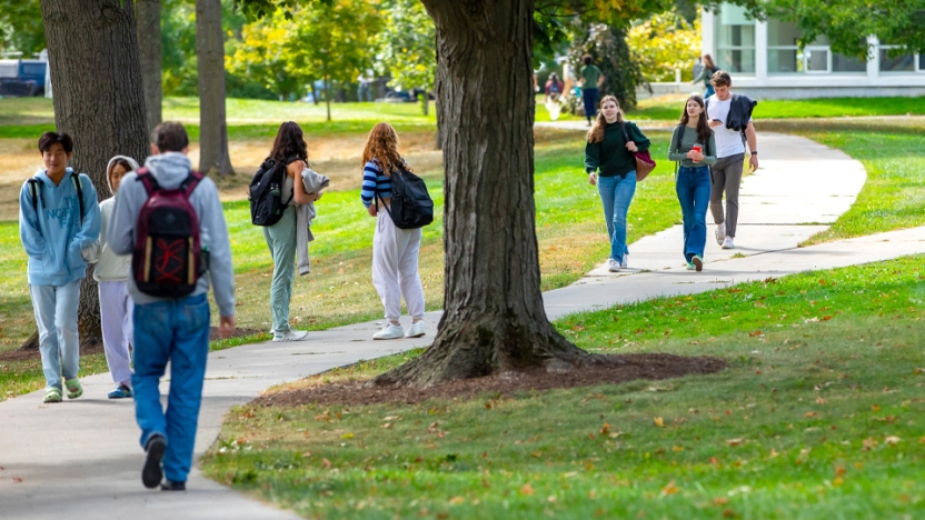 Students walking on the sidewalk through campus.