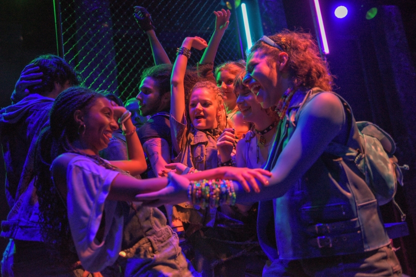 Party scene with everyone smiling and dancing, lots of colorful lighting