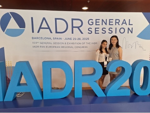 Two students in front of a sign for International Association for Dental Research.