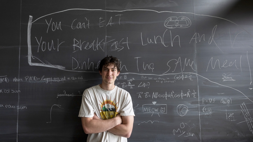 Sam standing in front of a chalkboard with his quote, “You can't eat your breakfast, lunch, and dinner in the same meal.”