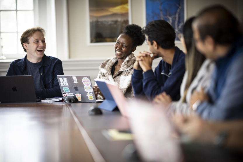 A group of students and their professor sit around a seminar table. 