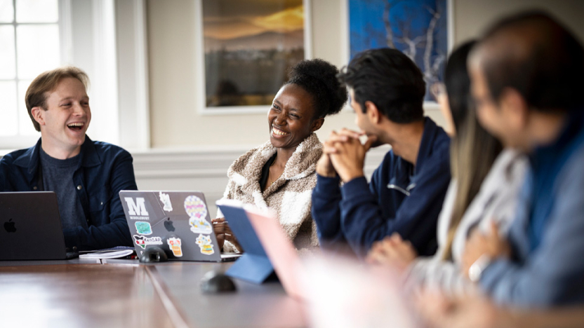 A group of students and their professor sit around a seminar table. 