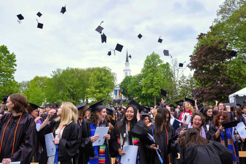Middlebury College graduates tossing mortar board caps in the air