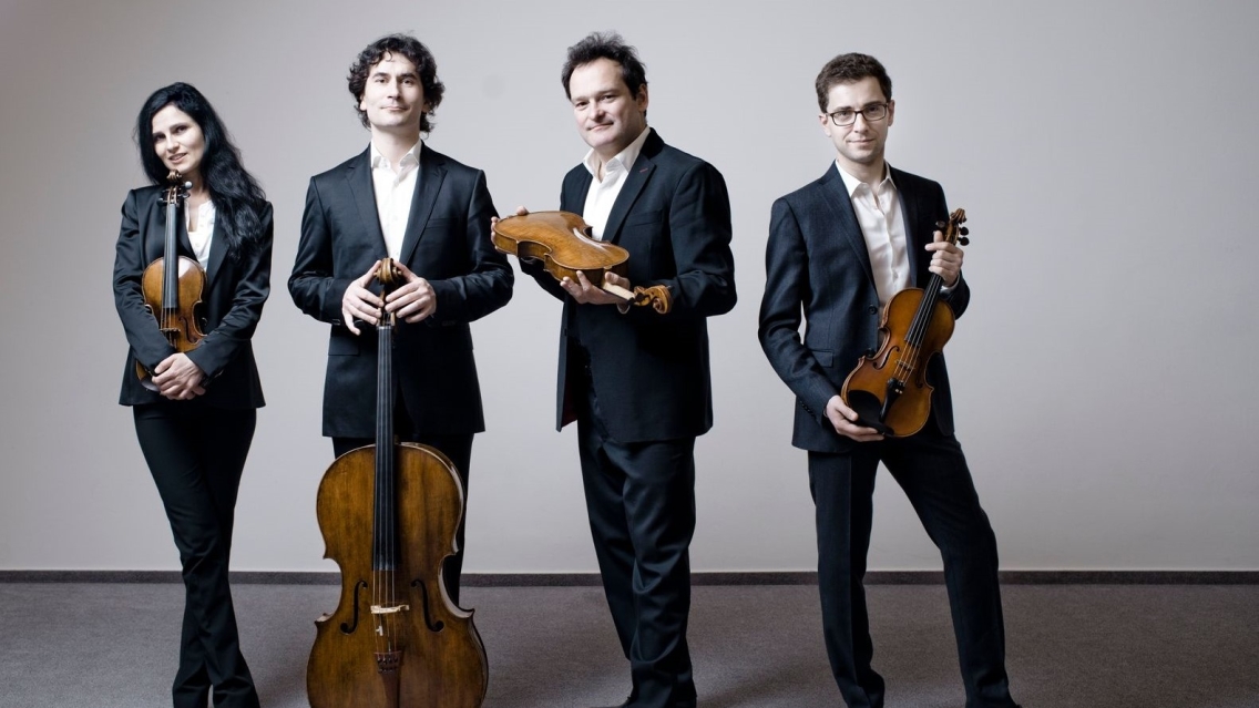 one female and three male musicians, standing, holding string quartet instruments