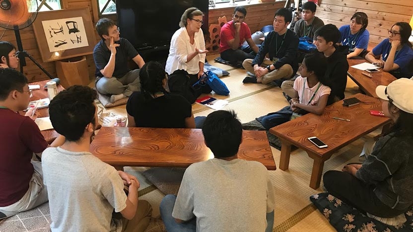 Students and a professor sit in a circle at the Japanese House.