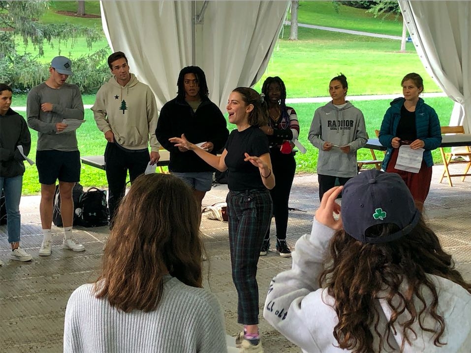 Students stand in a circle playing a game called "Reacting to the Past" under a canopy on the Middlebury campus.