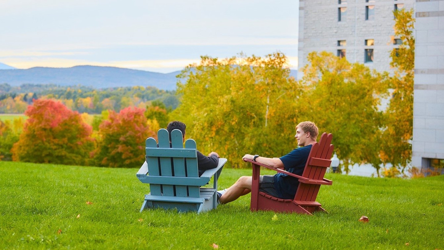 Students sit in Adirondack chairs on the Middlebury College campus.