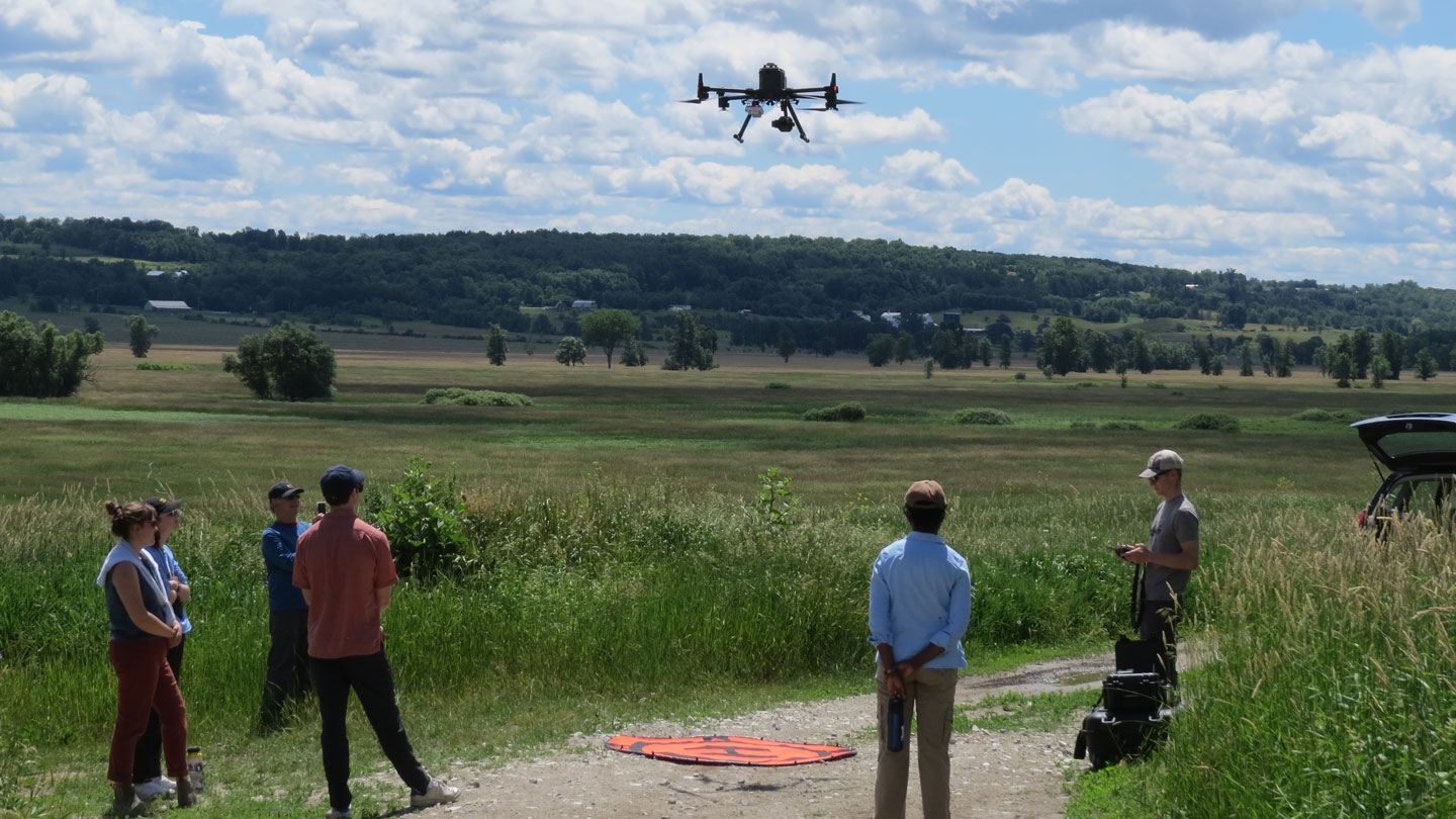 Students use a drone in the field to gather data.