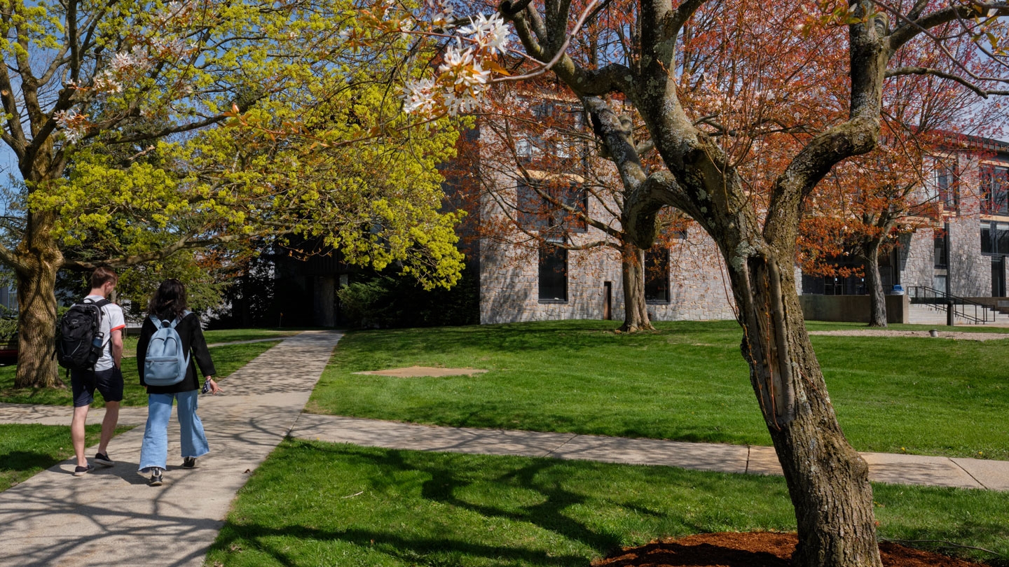 Two students walking on campus in the springtime.