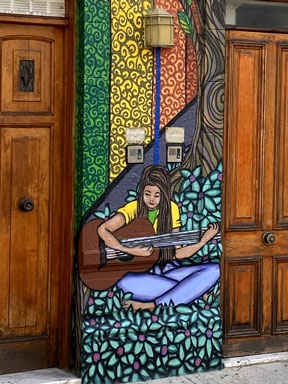 Graffiti painting of a woman playing a guitar on a street in Spain.